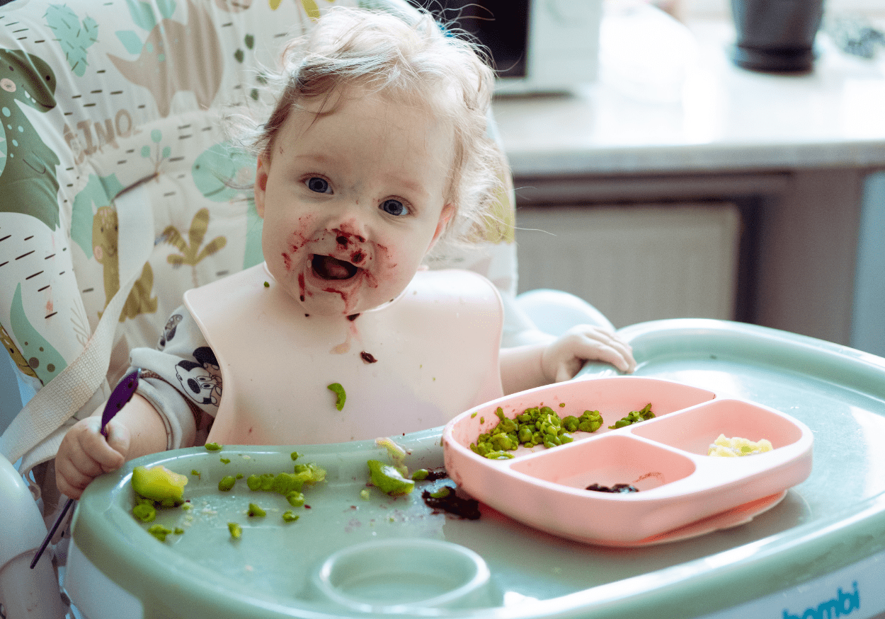 Bebê praticando BLW segurando alimento durante introdução alimentar